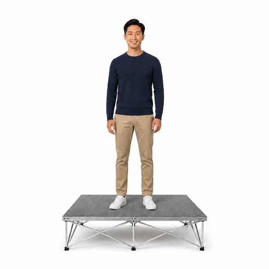 Man standing on a LimeLight modular portable stage with gray carpet finish.