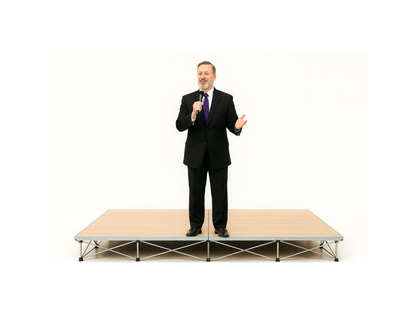 Man in a suit standing on a LimeLight Lite Series 8x8 modular stage platform in Wood Laminate at 8" height. Ideal for schools, churches, and event professionals.