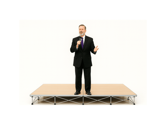 Man in a suit standing on a LimeLight Lite Series 8x8 modular stage platform in Wood Laminate at 8" height. Ideal for schools, churches, and event professionals.
